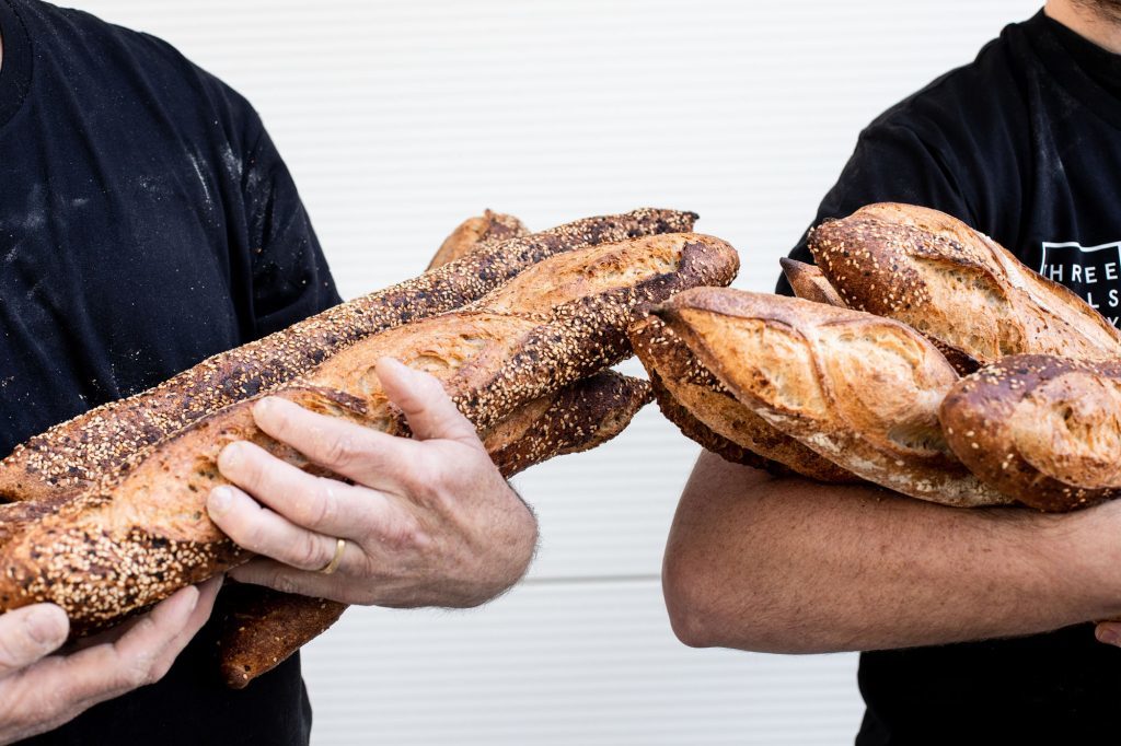 Hands holding multiple freshly baked baguettes